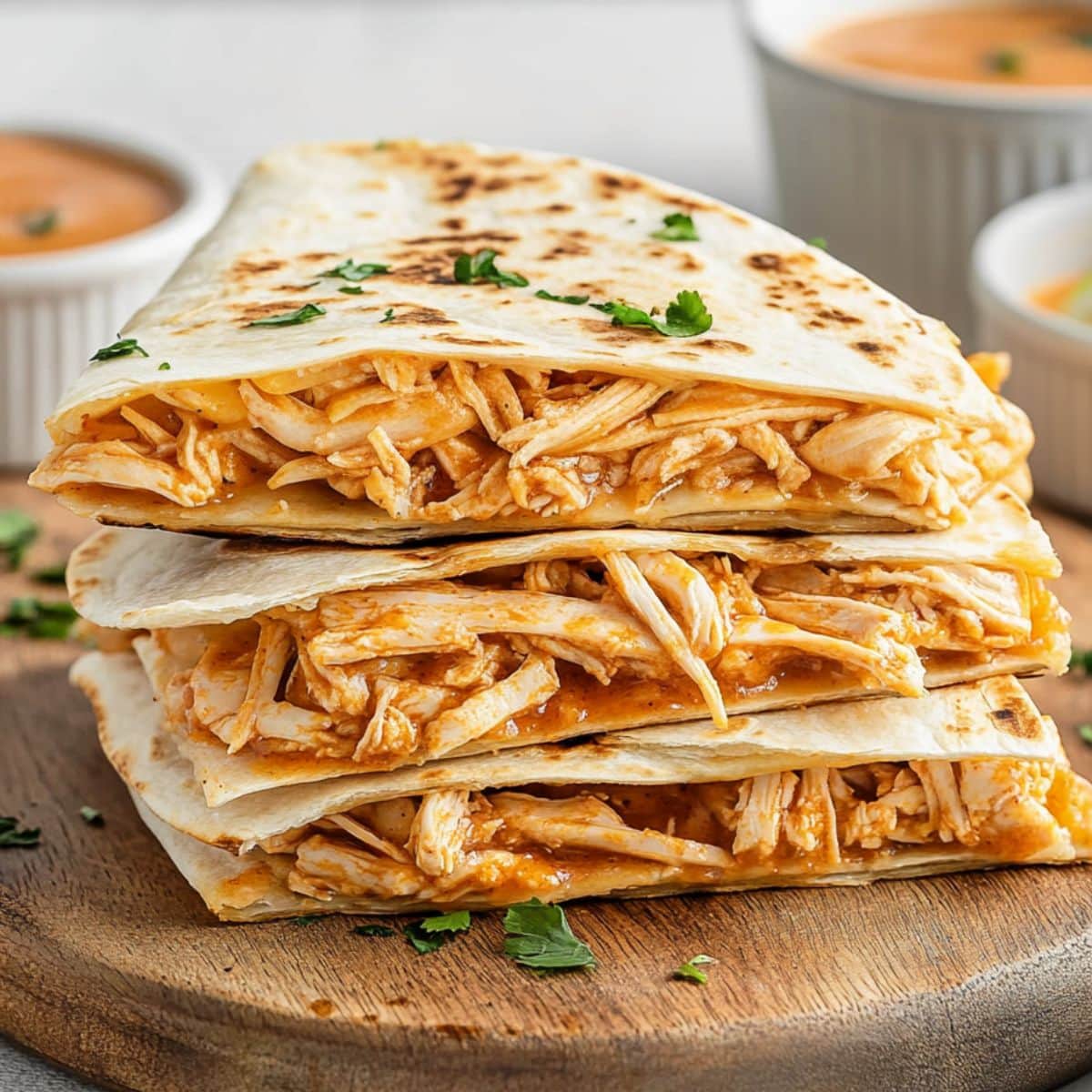 Sliced buffalo chicken quesadillas sitting on a wooden board.