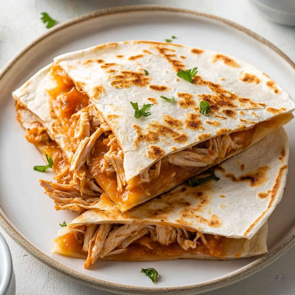 Sliced buffalo chicken quesadilla served in a white plate.