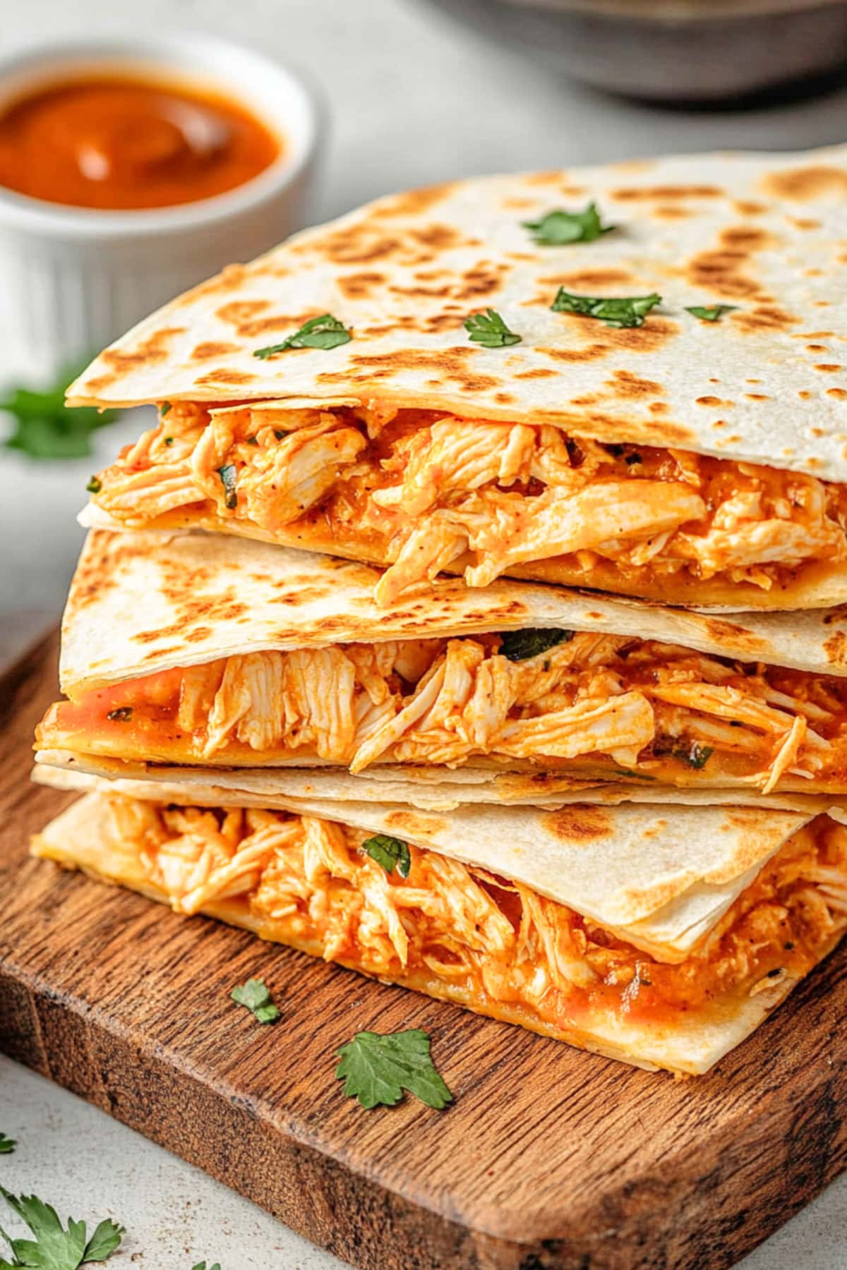 Shredded buffalo chicken filled quesadilla stacked in a wooden baord.