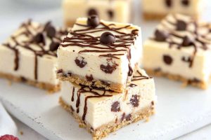 Cannoli cheesecake bars drizzled with chocolate syrup.