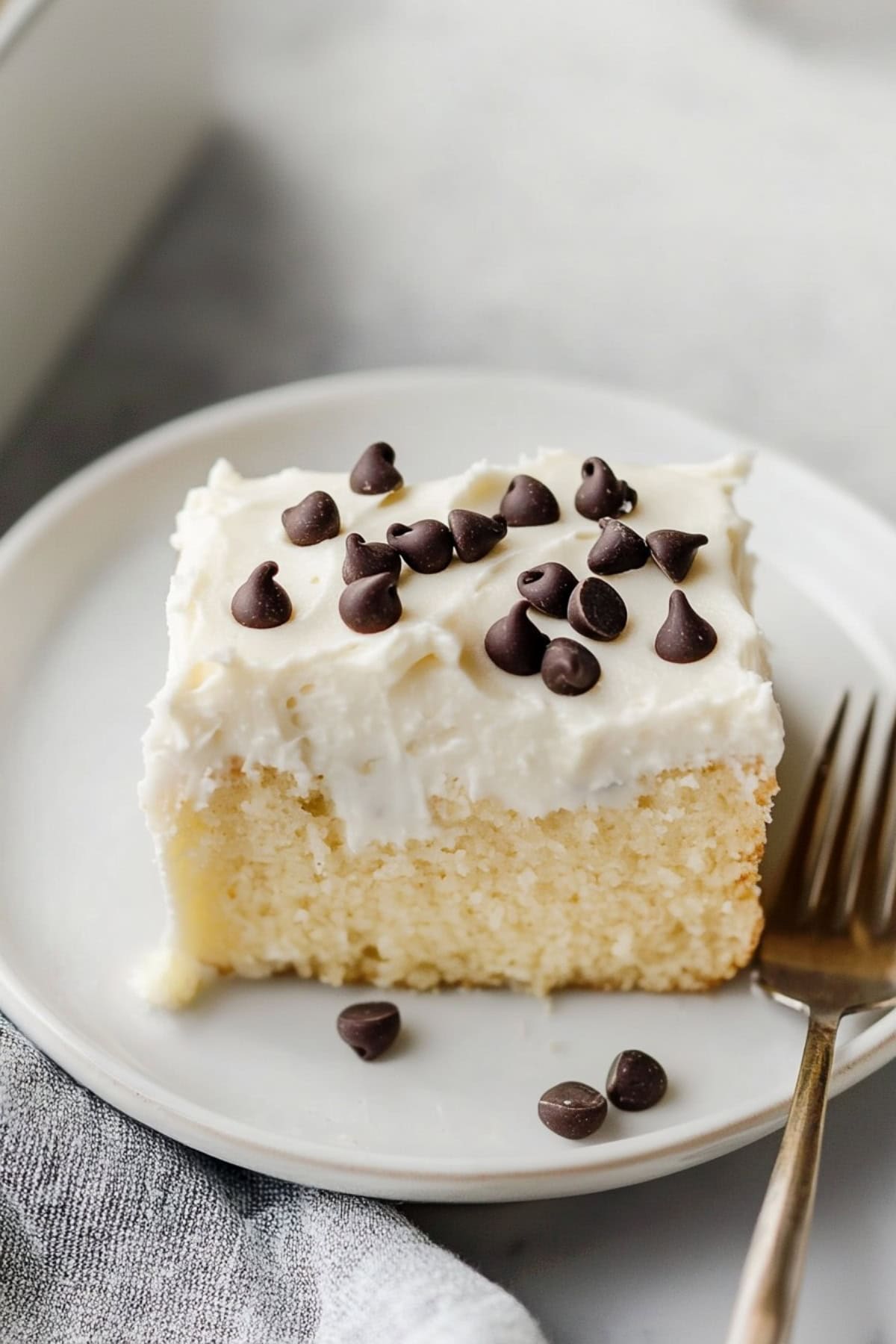 Sliced cannoli poke cake square with chocolate chips in a white plate.