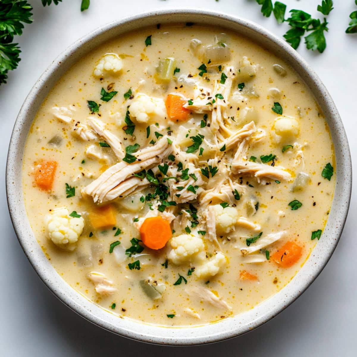 Cauliflower chicken soup with veggies in a bowl, top view