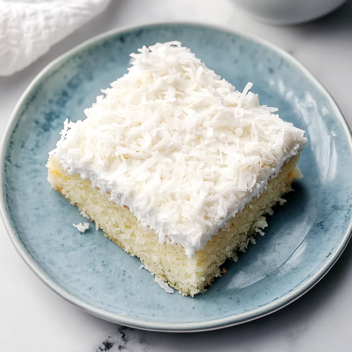 Close-up of a moist and soft coconut poke cake in a plate.