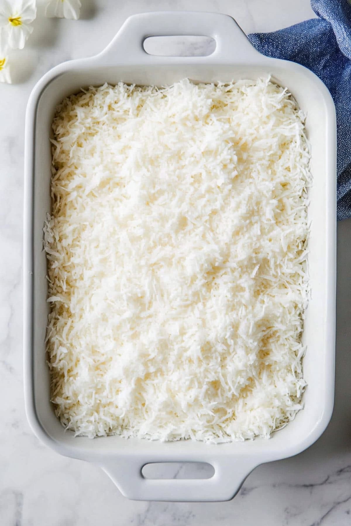 An overhead view of coconut poke cake in a baking pan.