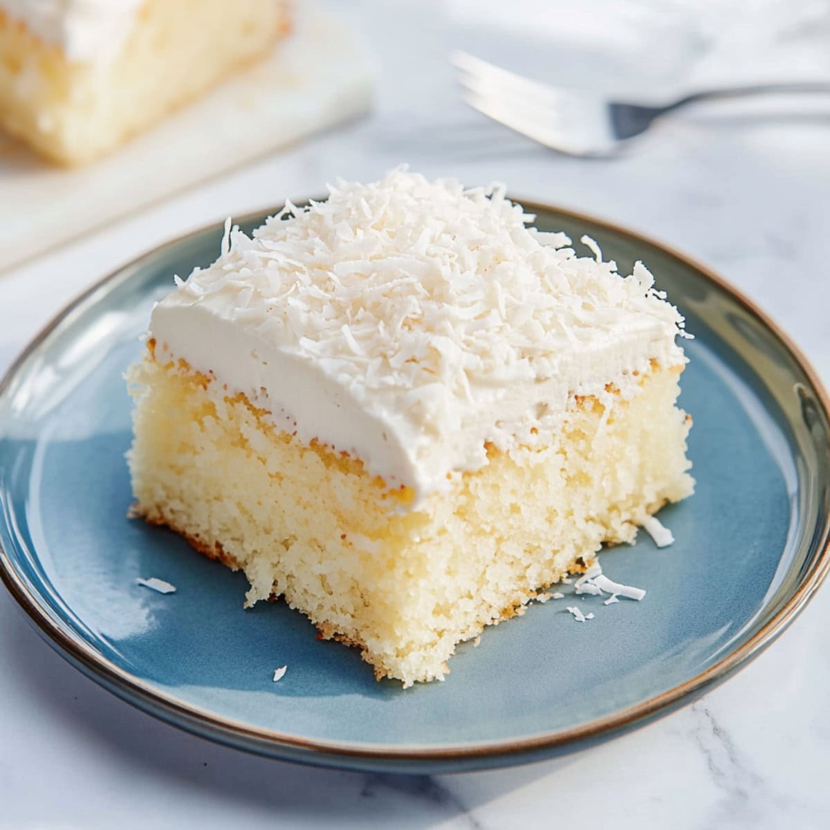 Sliced coconut poke cake in a plate.