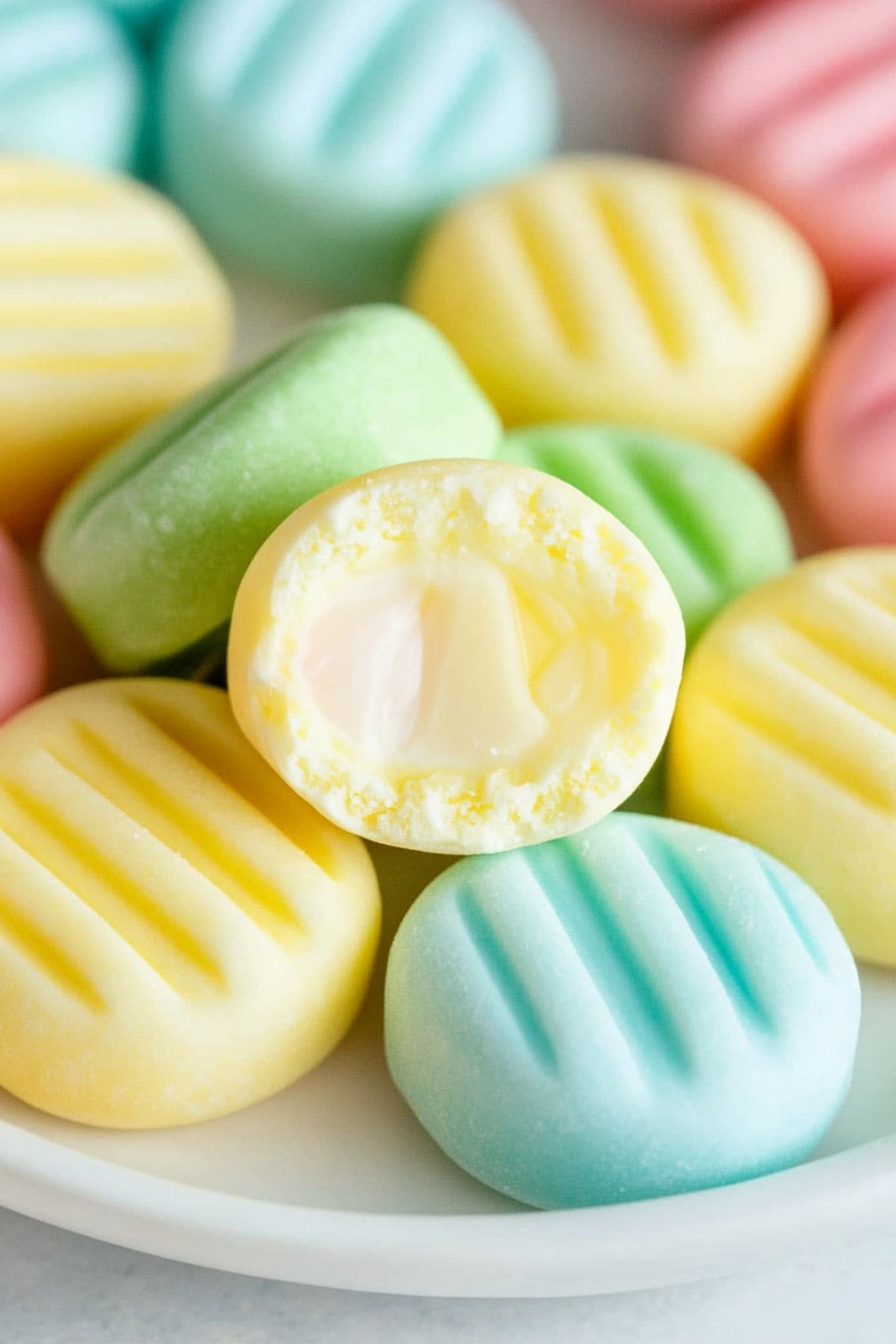 Bunch of colorful cream cheese mints in a white plate.