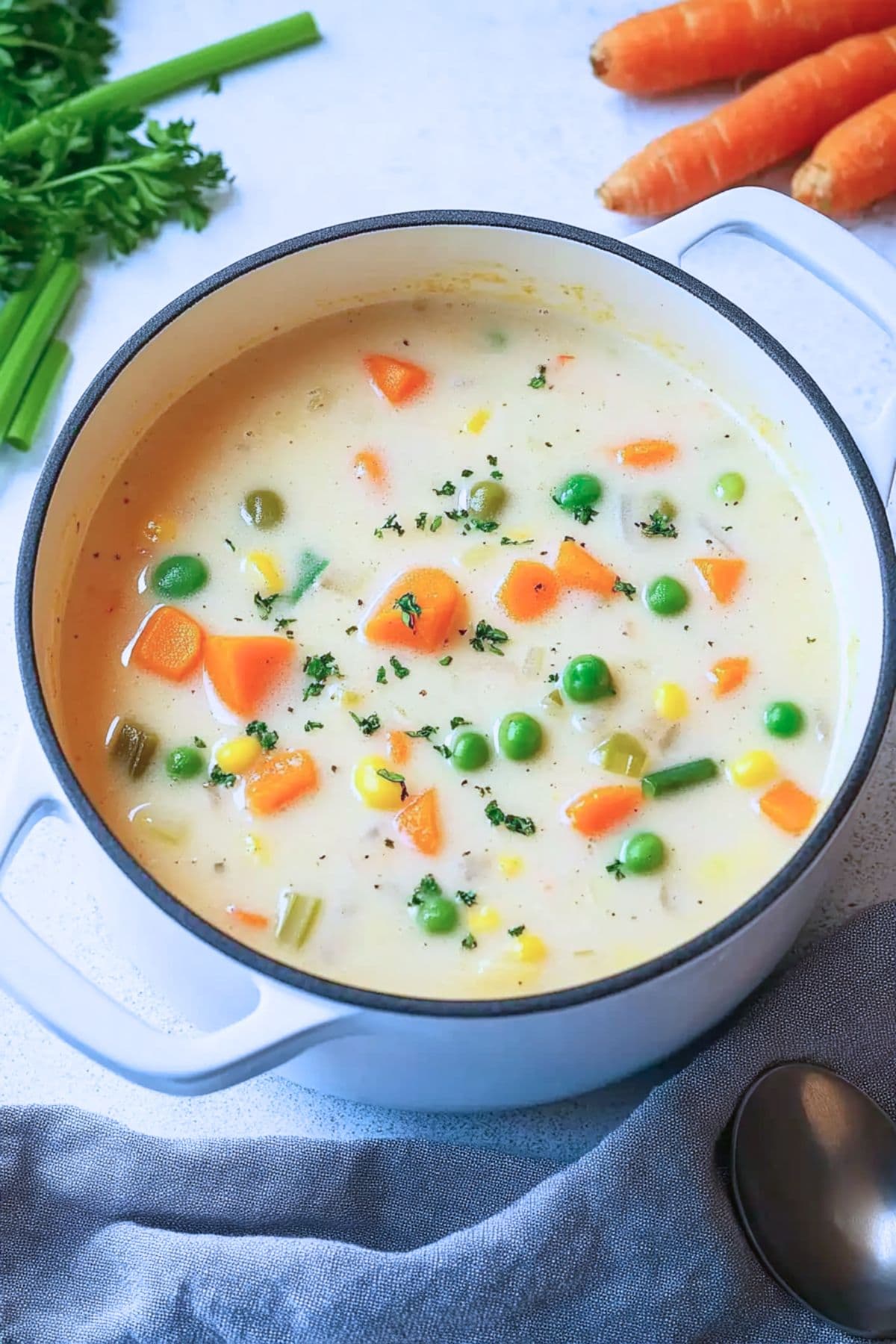 Creamy and thick soup with mixed veggies cooked in a white pot.