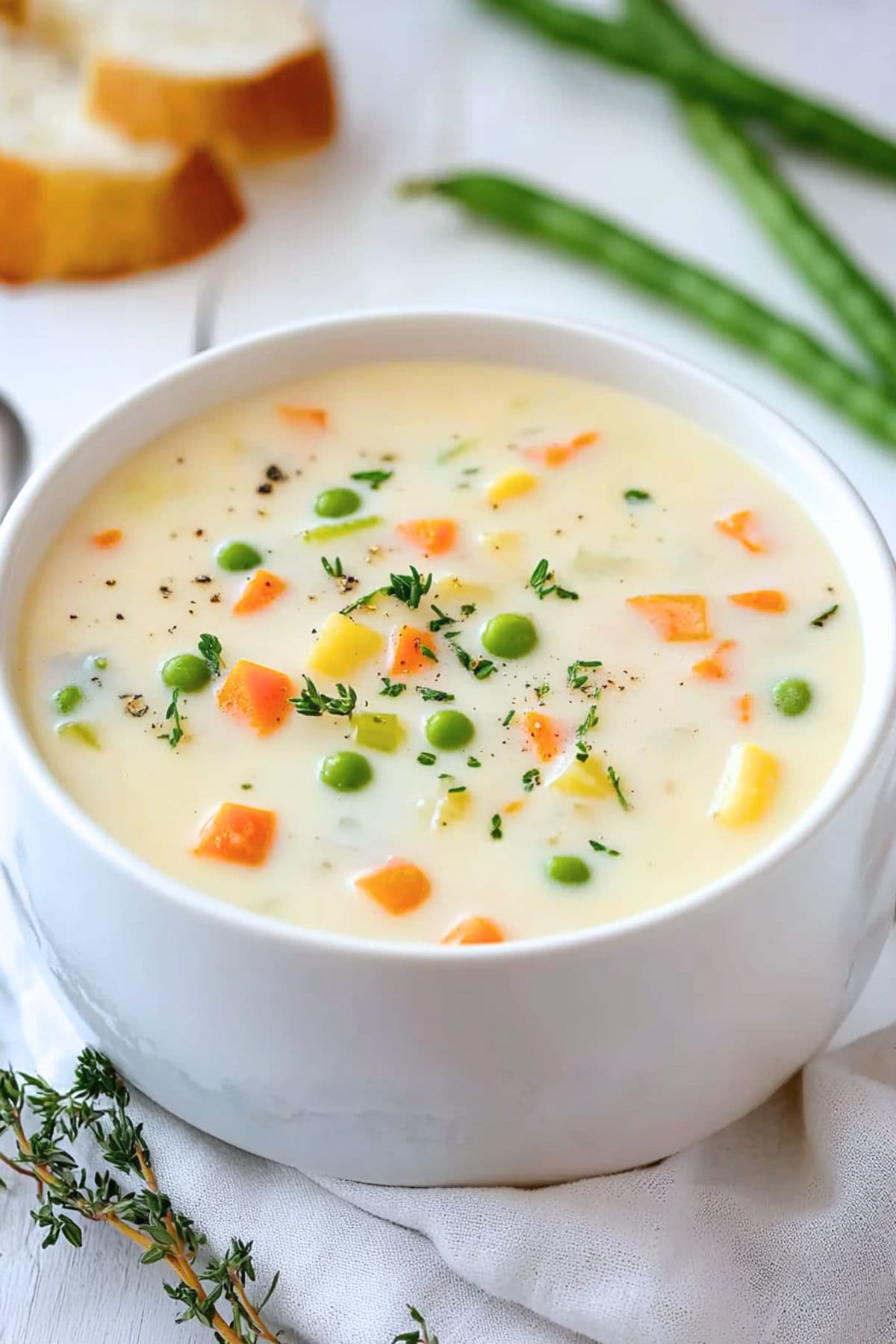 Creamy soup with mixed veggies in thick and creamy broth served in a white bowl. 