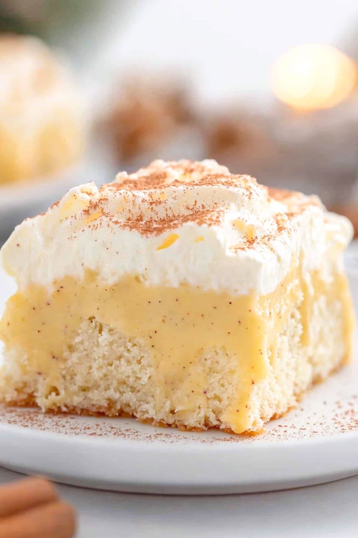 A slice of eggnog poke cake served in a white bowl dusted with nutmeg.