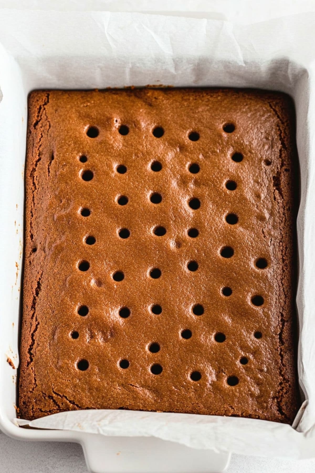 Gingerbread in a baking dish with parchment paper with holes all over it.