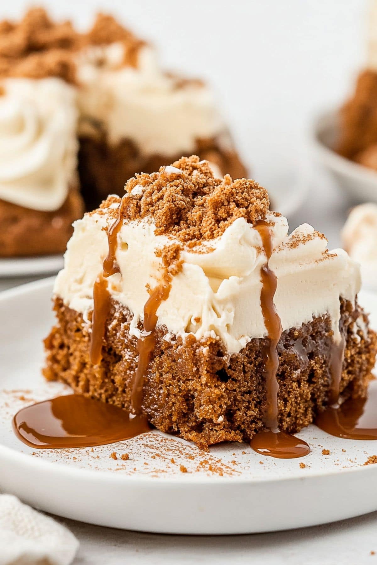 Square slice serving of gingerbread poke cake with drizzled of caramel syrup and crushed gingerbread cookies on top.