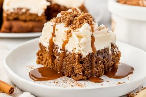 Gingerbread poke cake square slice drizzled with caramel sauce served in a white plate.