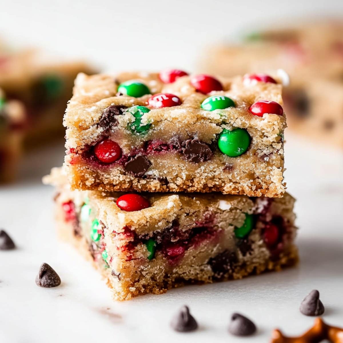 A stack of Christmas cookie bars, featuring golden brown edges, chocolate chips and colorful candies.