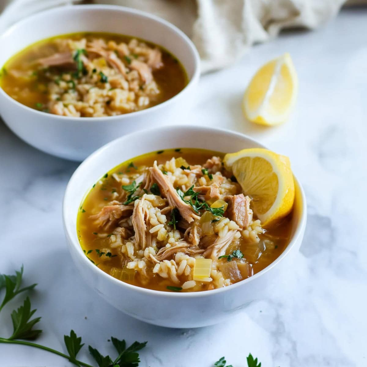 Bowls of turkey and rice soup, garnished with lemon.