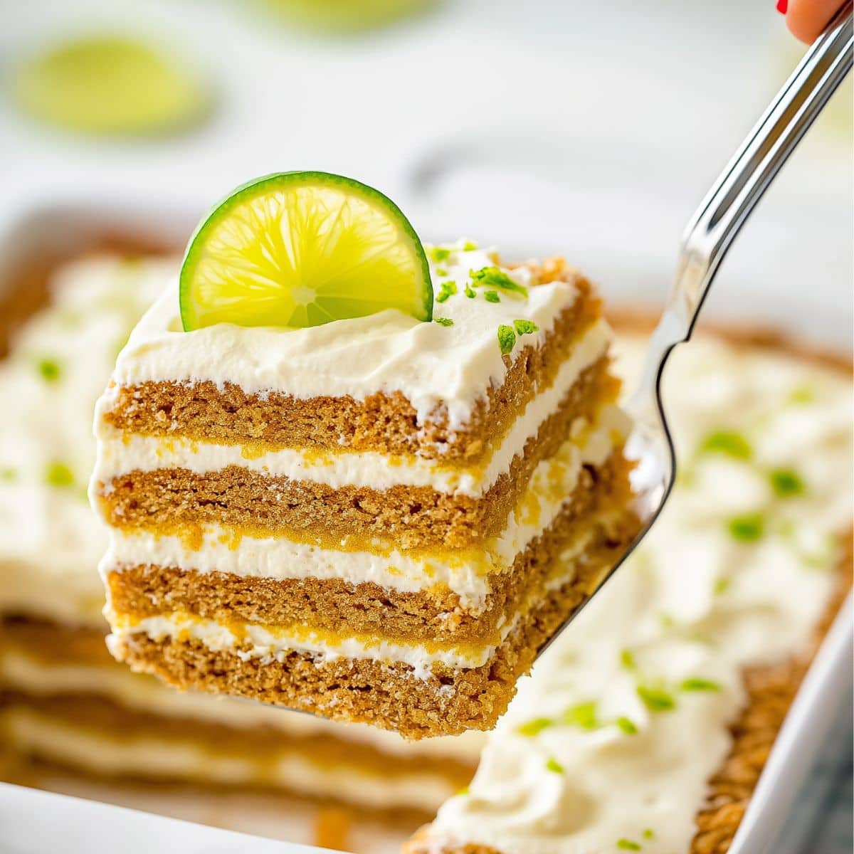 Pie ladle lifting a slice of key lime icebox cake from baking dish.