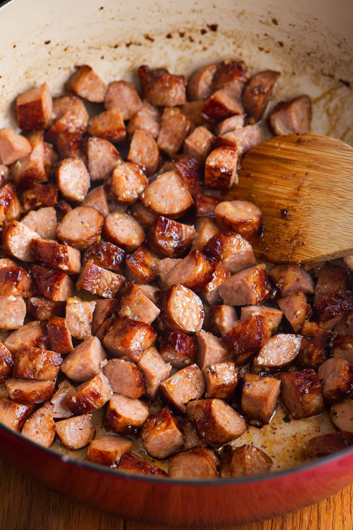 Cooked Kielbasa sausage in a red Dutch oven, close-up