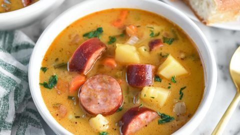 Two bowls of Kielbasa potato soup with carrots and onions.