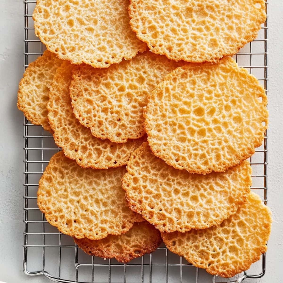 Lace cookies sitting on a wire cooling rack.