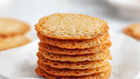 Stack of crispy thin lace cookies stacked on top of a white plate.