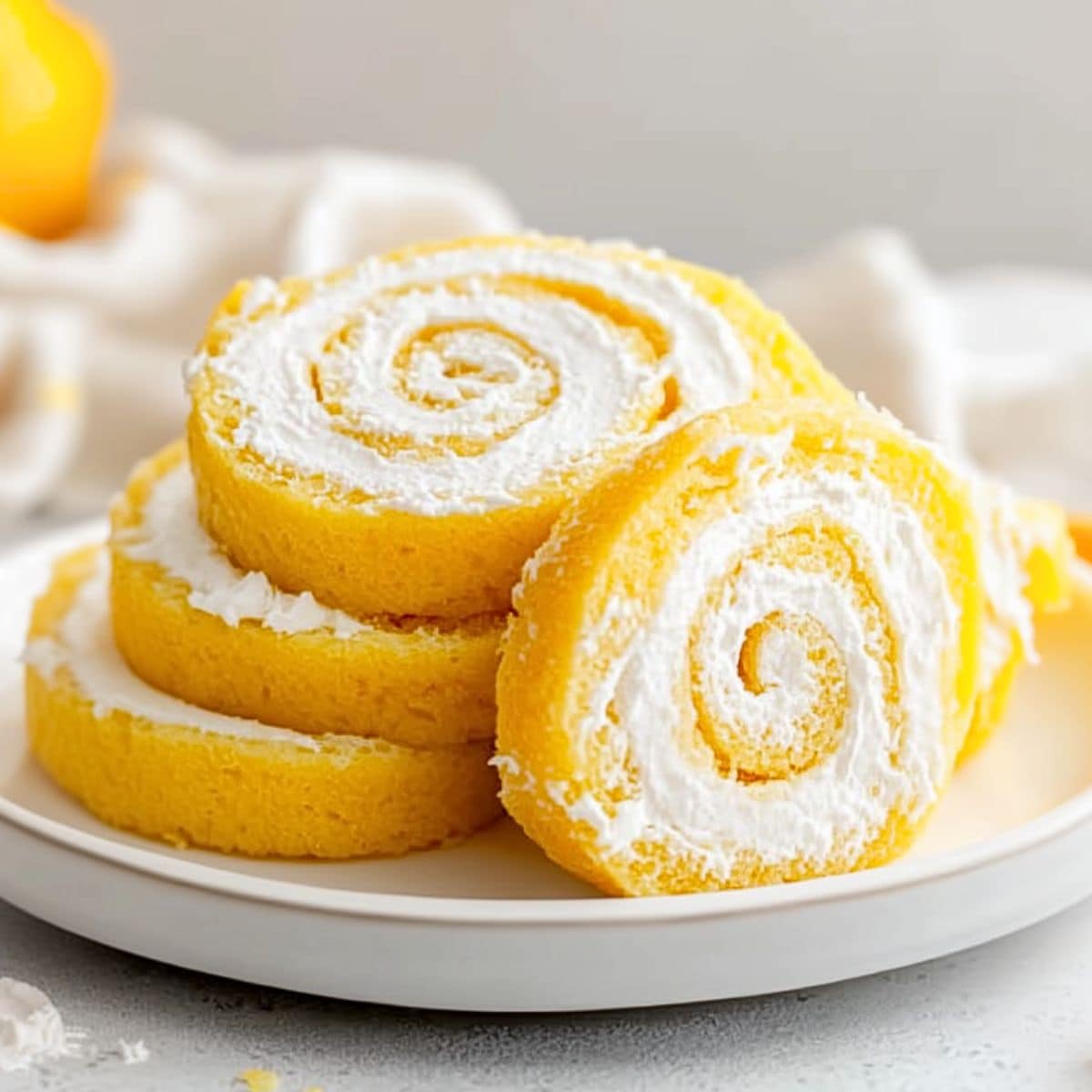 Sliced lemon cake roll served un a white plate. 