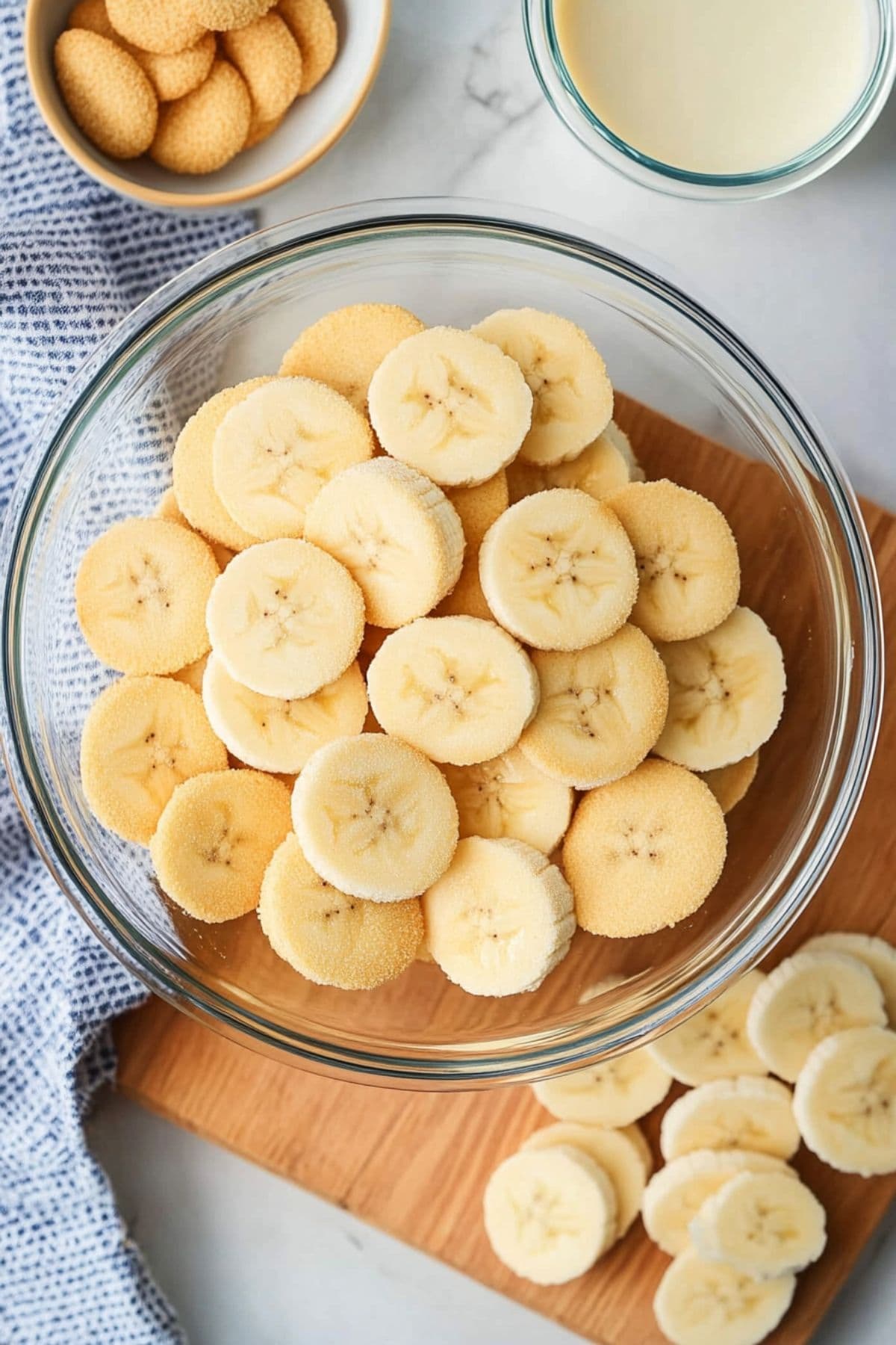 Sliced bananas in a glass bowl sitting next to Nila wafers in a small bowl.