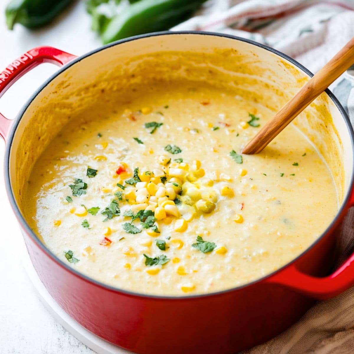 Creamy Mexican corn soup cooked in a red pot.