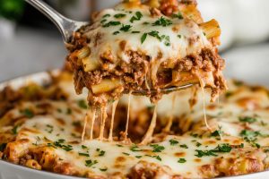 Mouthwatering cheesy million dollar baked ziti with ground beef and sprinkled with chopped parsley.