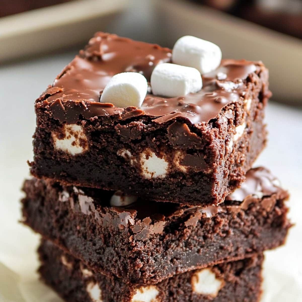 A close-up of a thick, chocolatey Mississippi Mud Brownies, topped with marshmallows, stacked