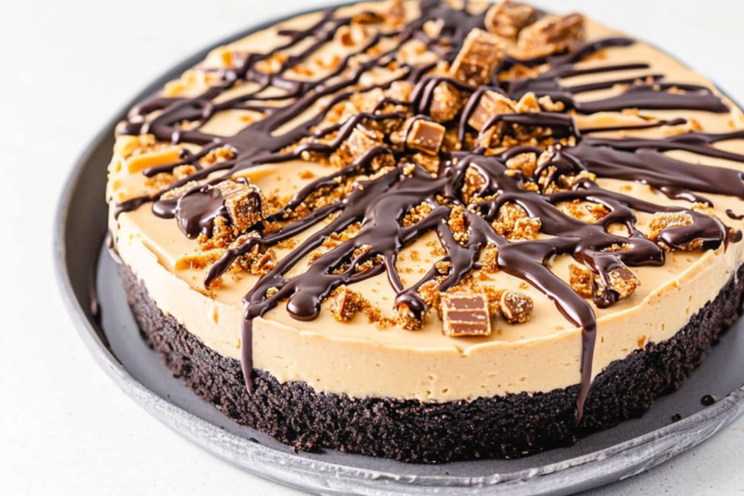 No Bake butterfinger pie with chocolate crust sitting on a large plate.