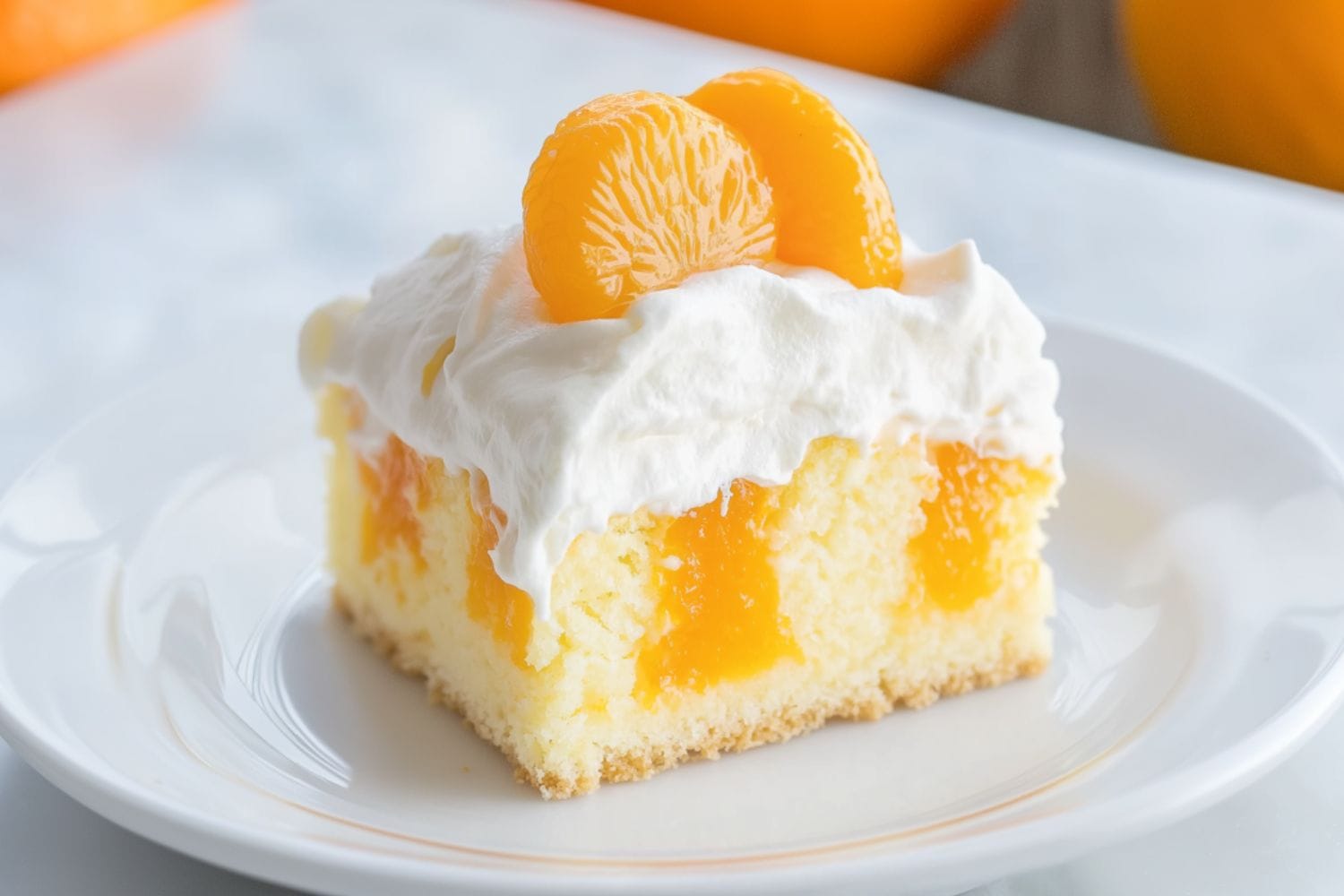 Square slice pf orange poke cake with orange meat garnish and a layer of whipped cream on top served in a white plate.