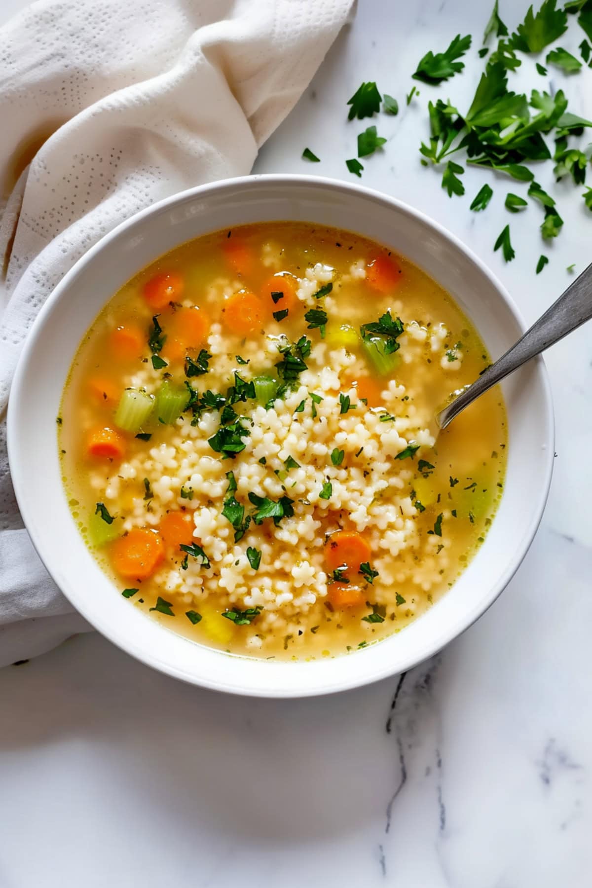 A simple bowl of pastina soup, with tiny pasta cooked in a rich, light broth with chopped carrots and celery.