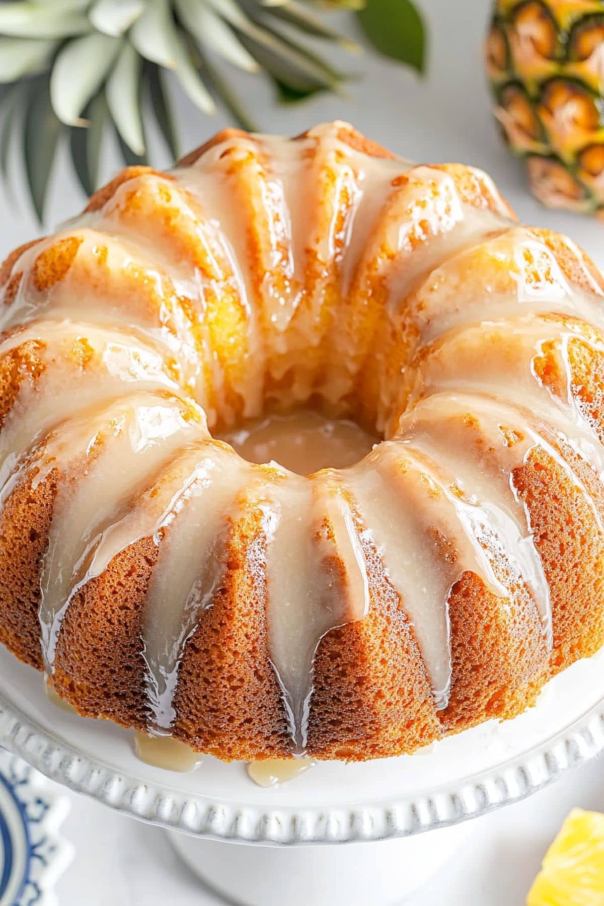 Pound cake drizzled with sugar glaze on top sitting on a cake tray, pineapple in the background.