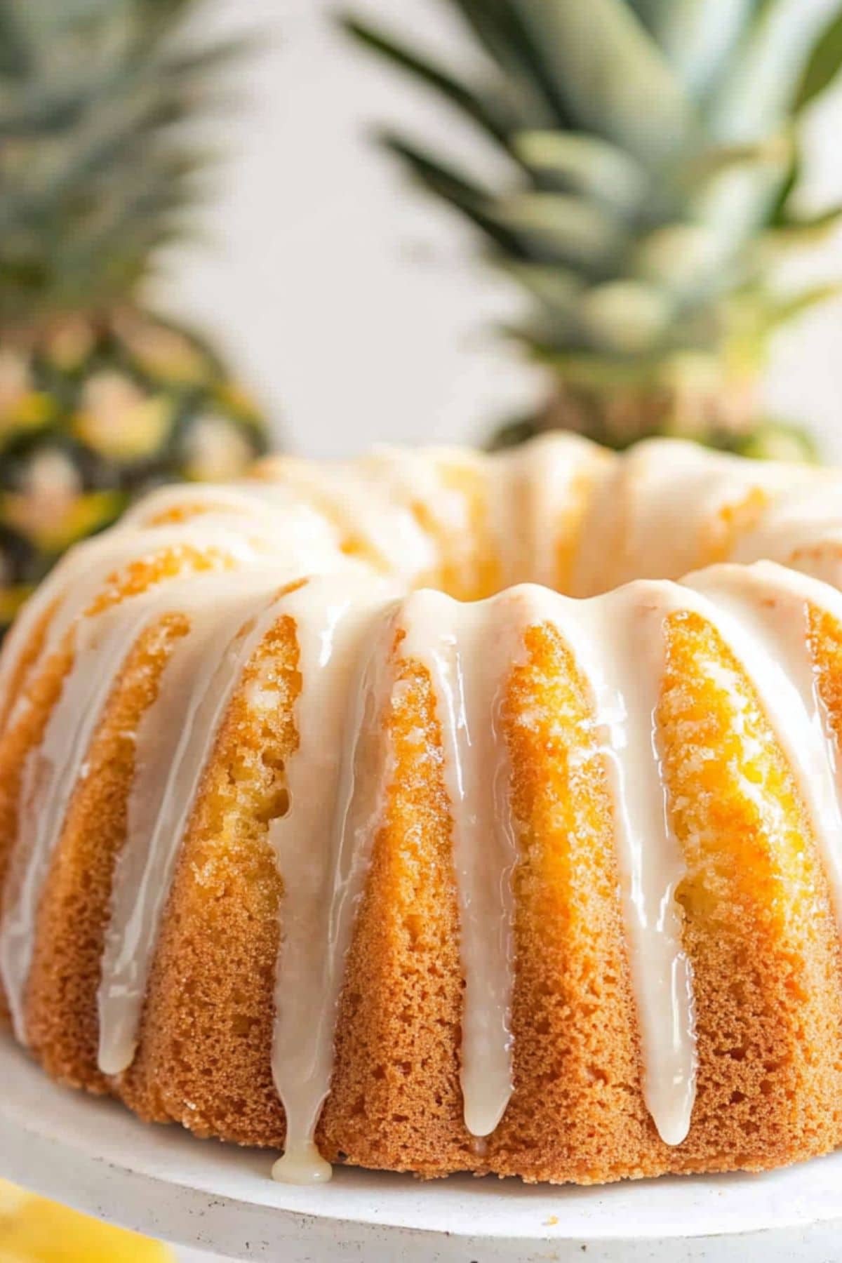 Pineapple pound cake drizzled with sugar glaze on top sitting on a cake tray.
