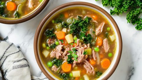 Top-down view of two scotch broth bowls with lamb and vegetables.