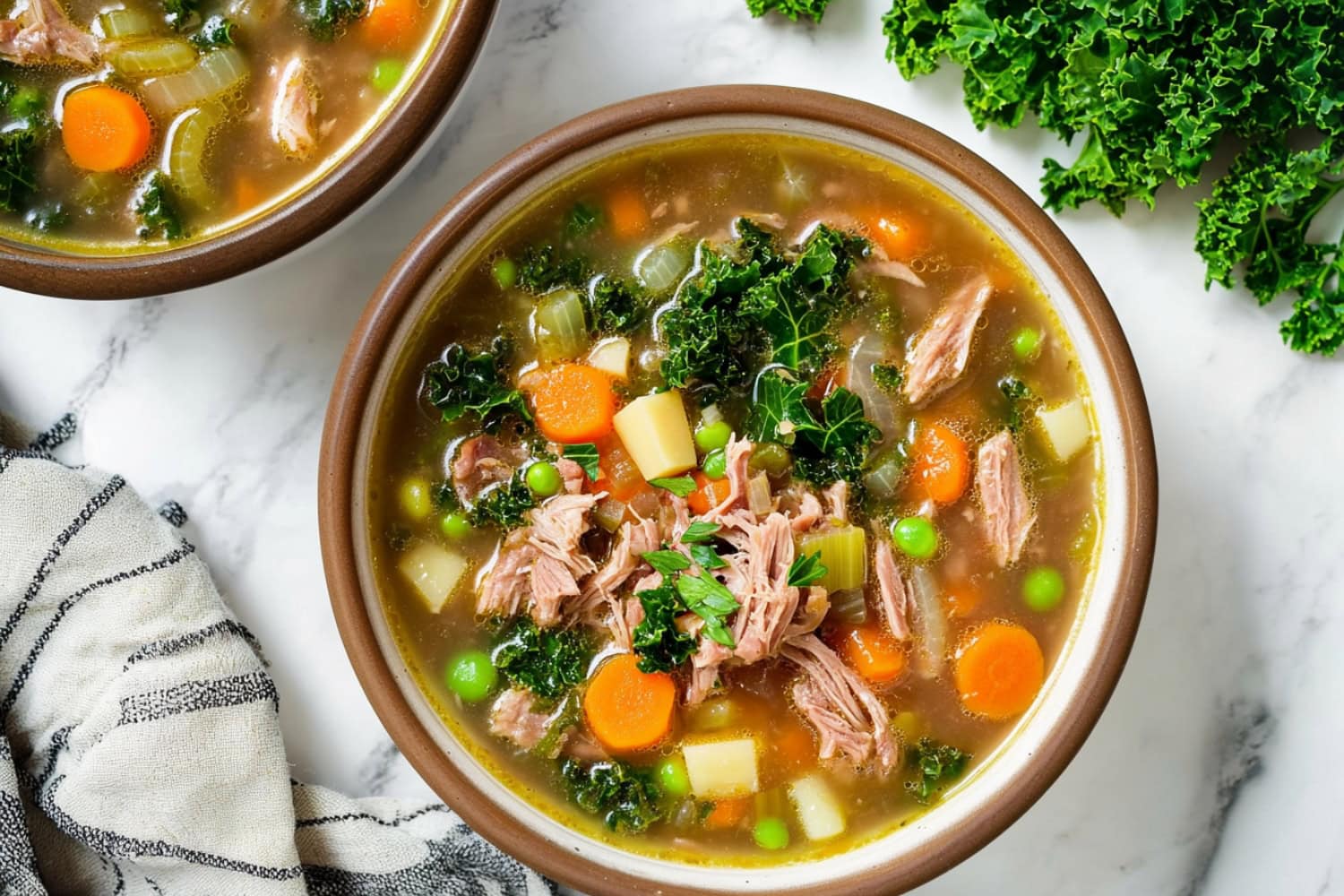 Top-down view of two scotch broth bowls with lamb and vegetables.