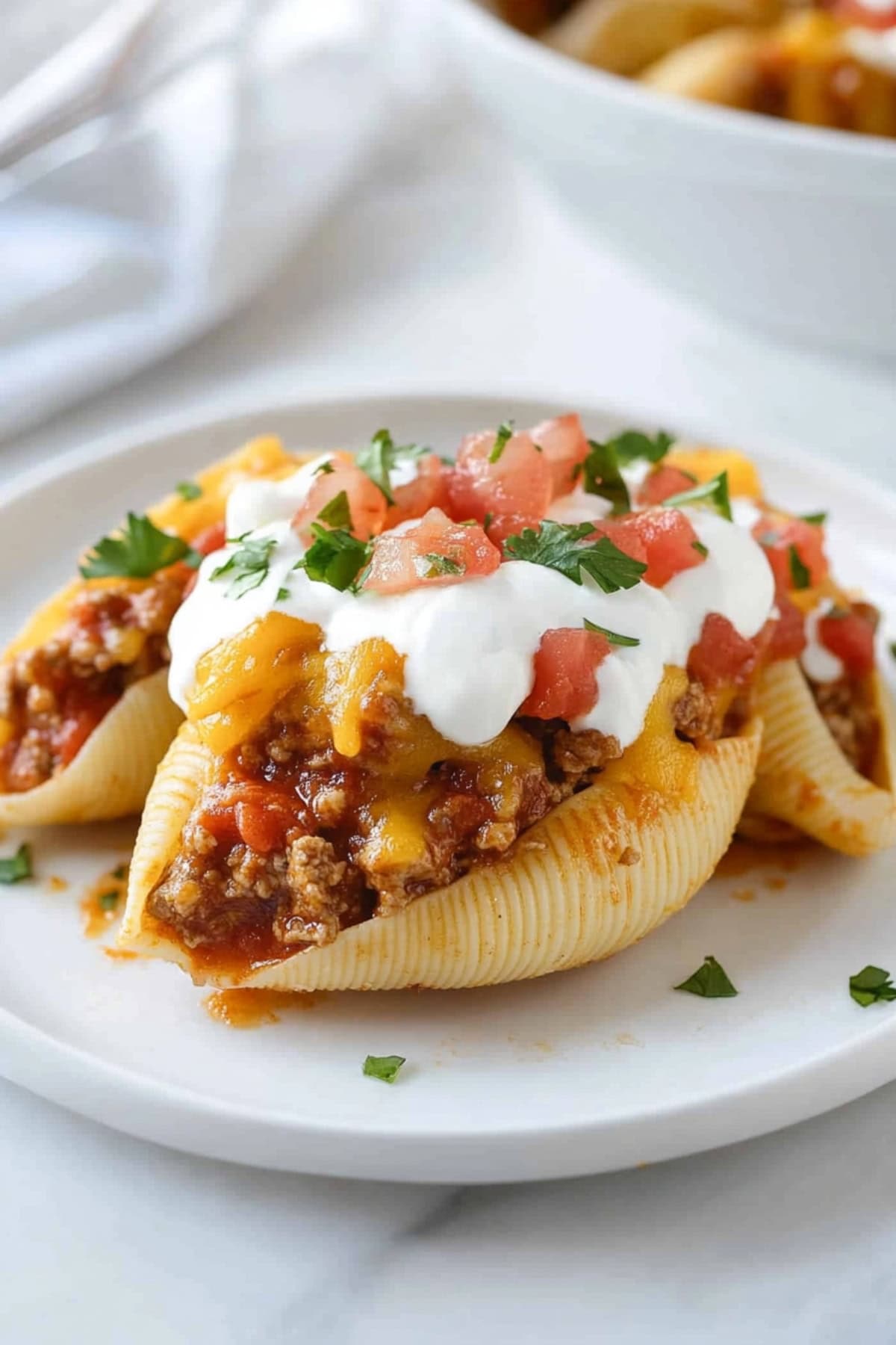 Serving of taco stuffed shells topped with sour cream on a plate