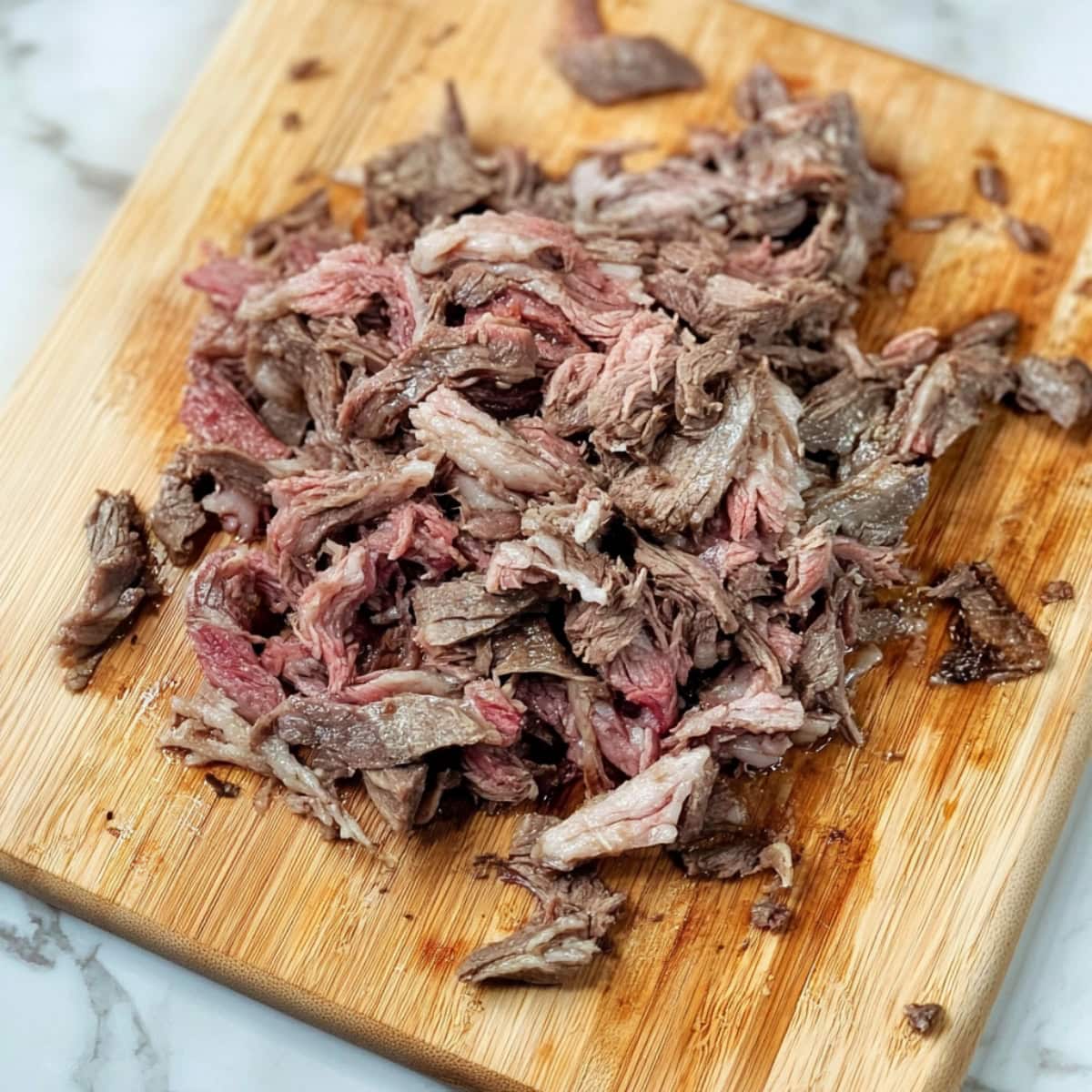 Shredded lamb in a wooden cutting board.