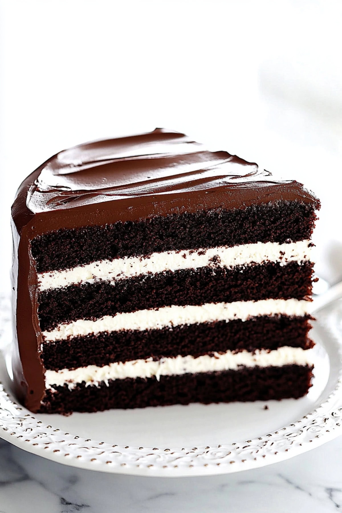 Slice of Dark Chocolate Cake with Vanilla Frosting and Ganache Coating