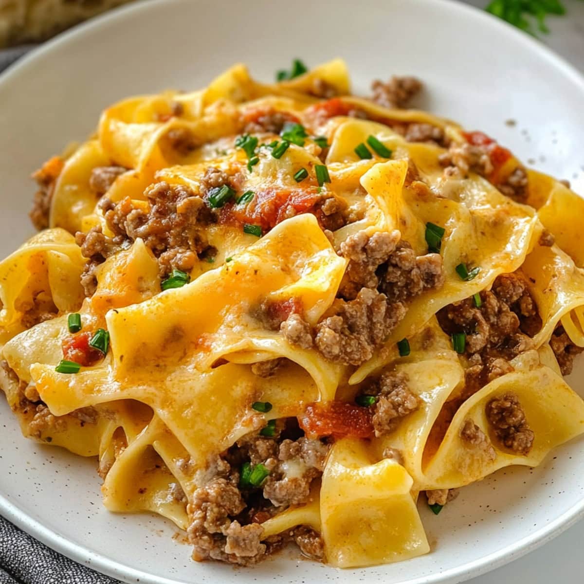 A savory serving of sour cream noodle bake with layers of ground beef, pasta, and creamy sauce.