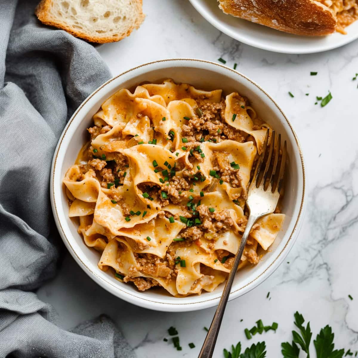 Creamy homemade sour cream noodle bake with ground beef and topped with chopped chives.