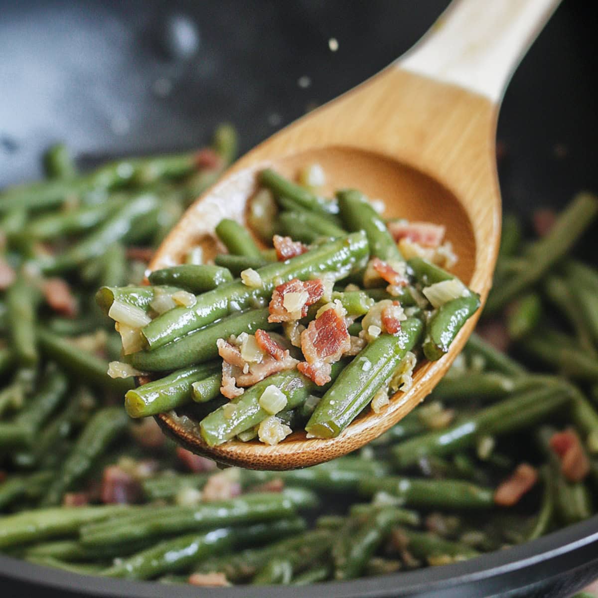 Wooden ladle filled with a scoop serving sauteed green beans with bacon.