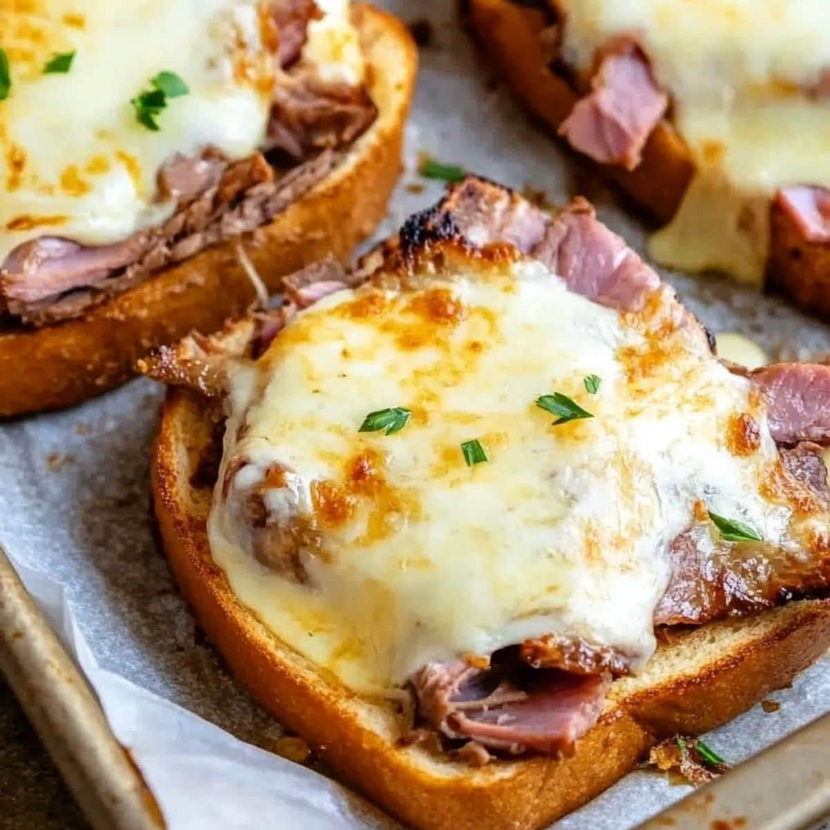 Texas French toast topped with thinly sliced roast beef arranged in a baking sheet with parchment paper.