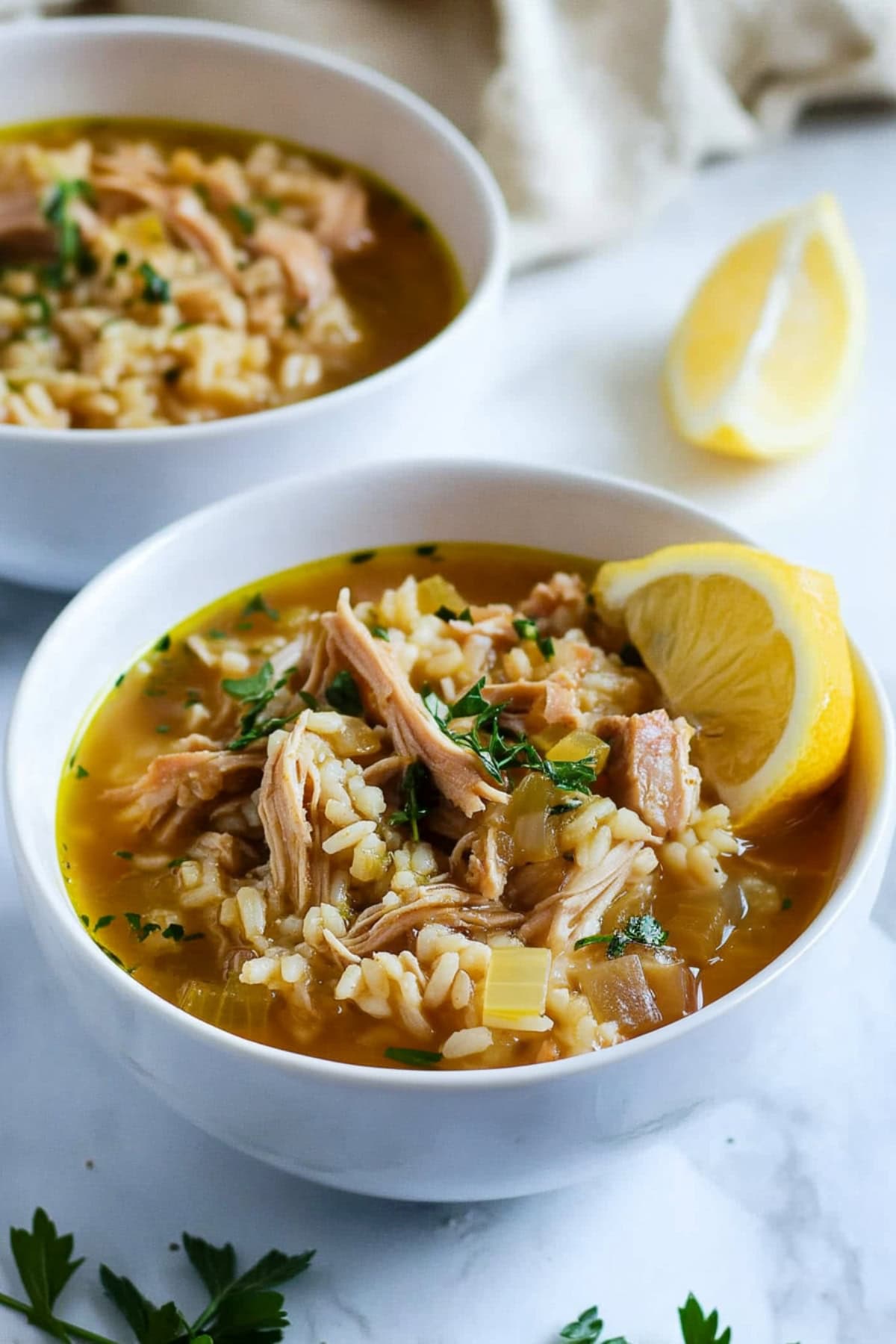 Two bowls of turkey and rice soup, garnished with lemon.