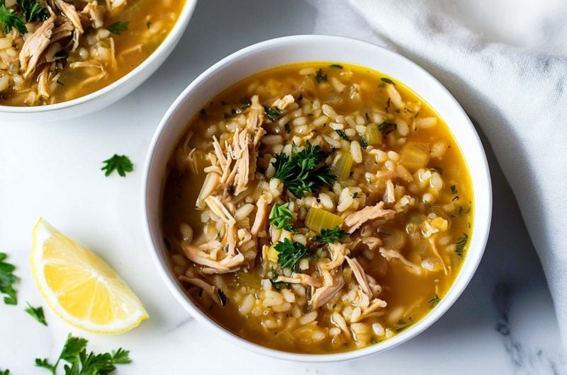 Turkey and rice soup with herbs and garnished with a lemon wedge.