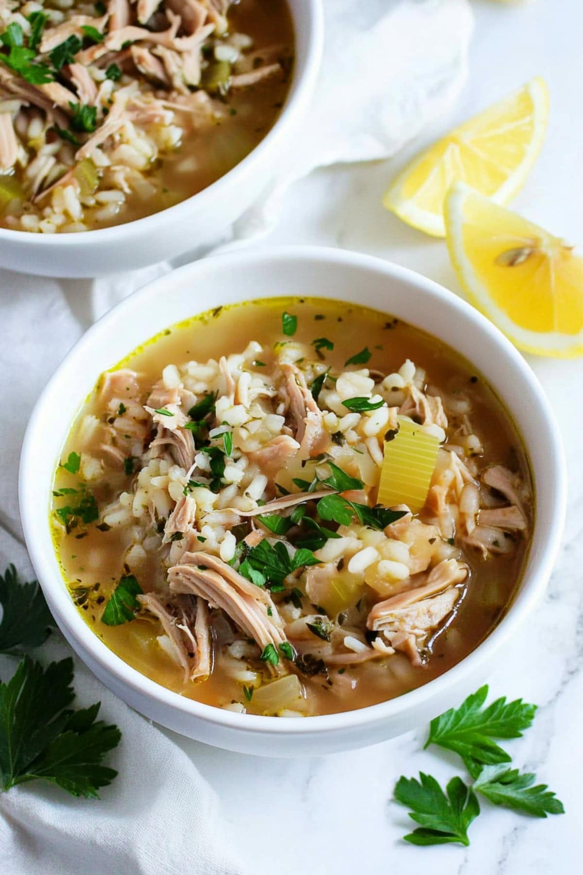 Turkey and rice soup with a clear, flavorful broth and green herbs.