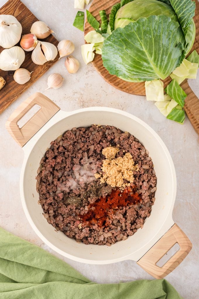 Browned ground beef topped with garlic and spices in a Dutch oven
