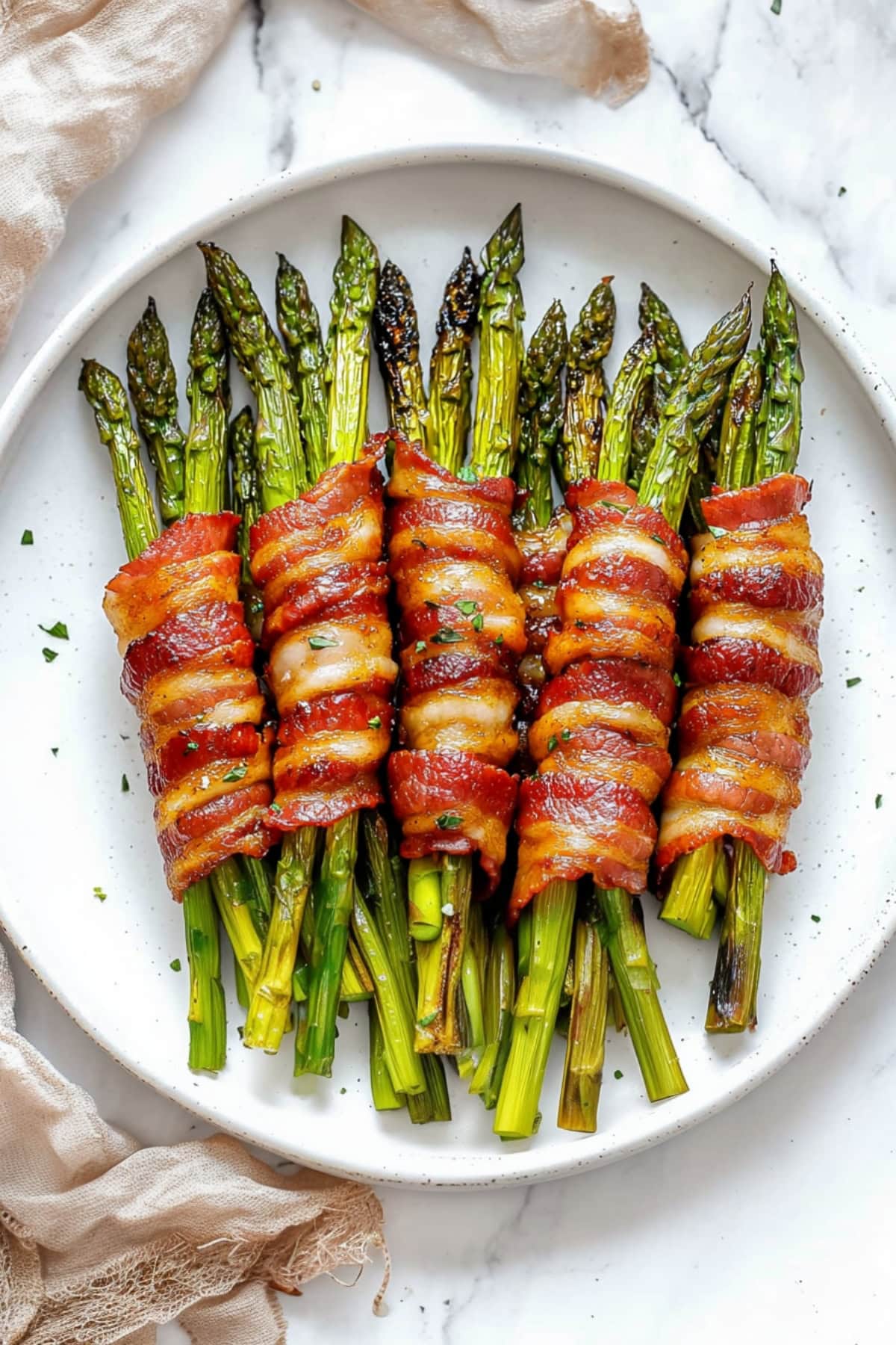 An overhead view of bacon wrapped asparagus in a plate.