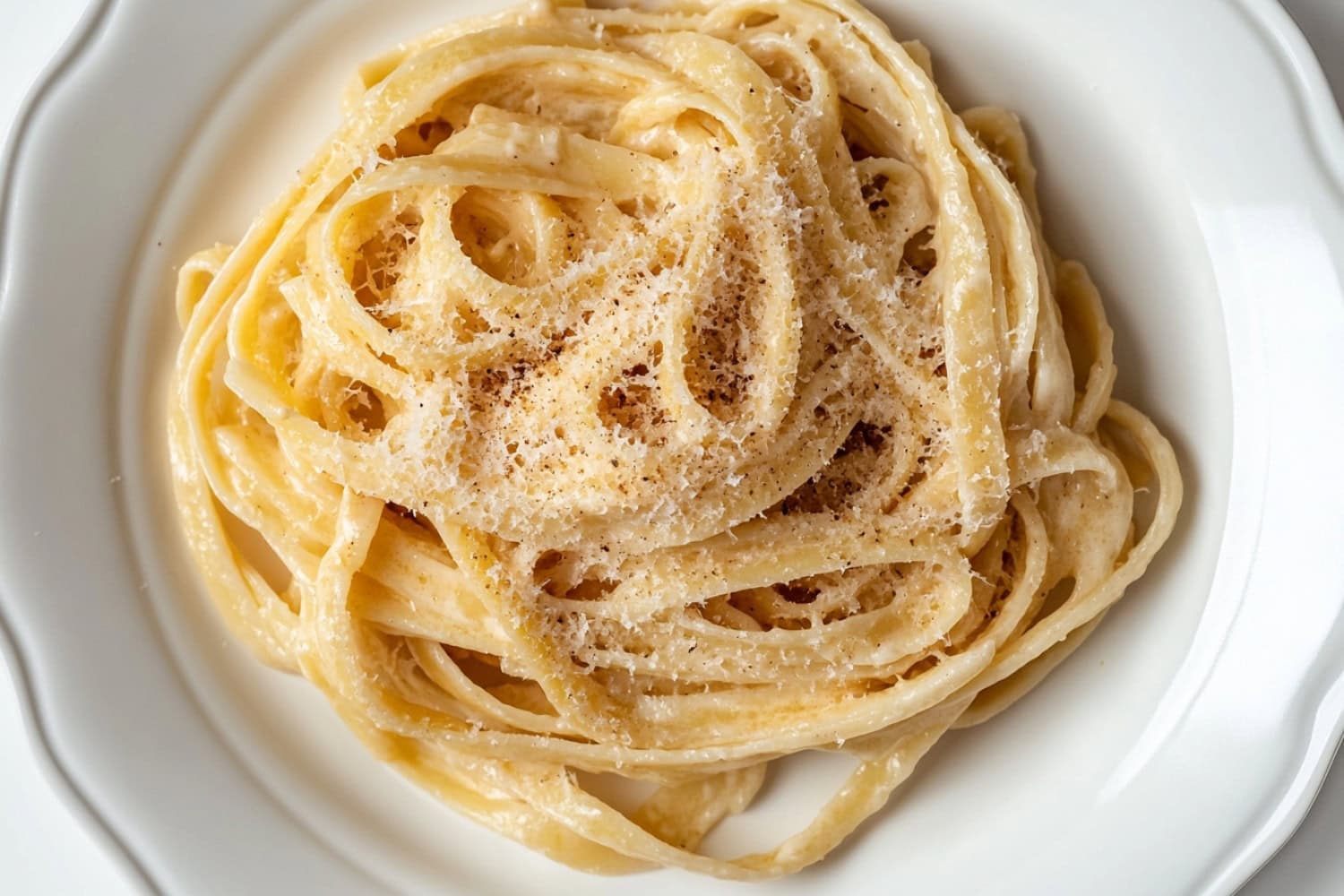 Browned butter fettucine alfredo served in a plate sprinkled with parmesan cheese on top.