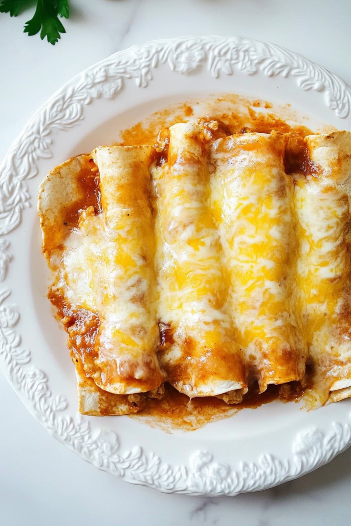 Serving of cheesy enchiladas in a plate, top view