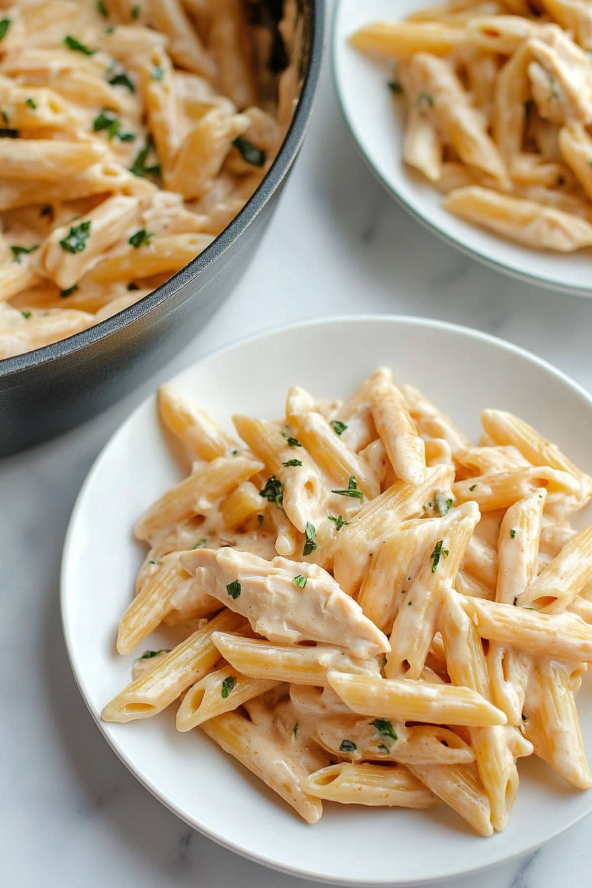 Creamy penne with chicken served in a white plate.